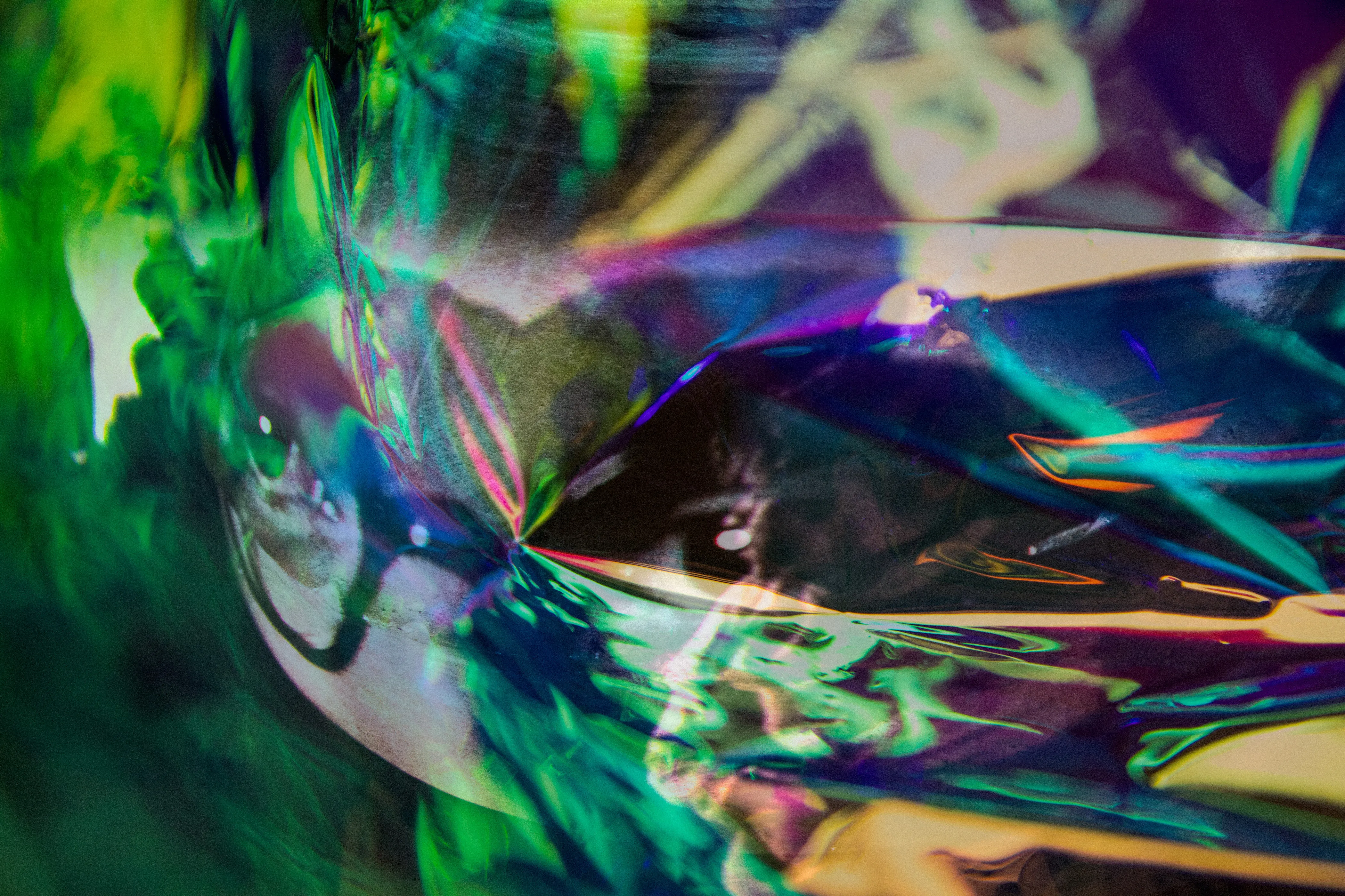 Green, blue and silver foil with a pale face partly visible at the lower left.