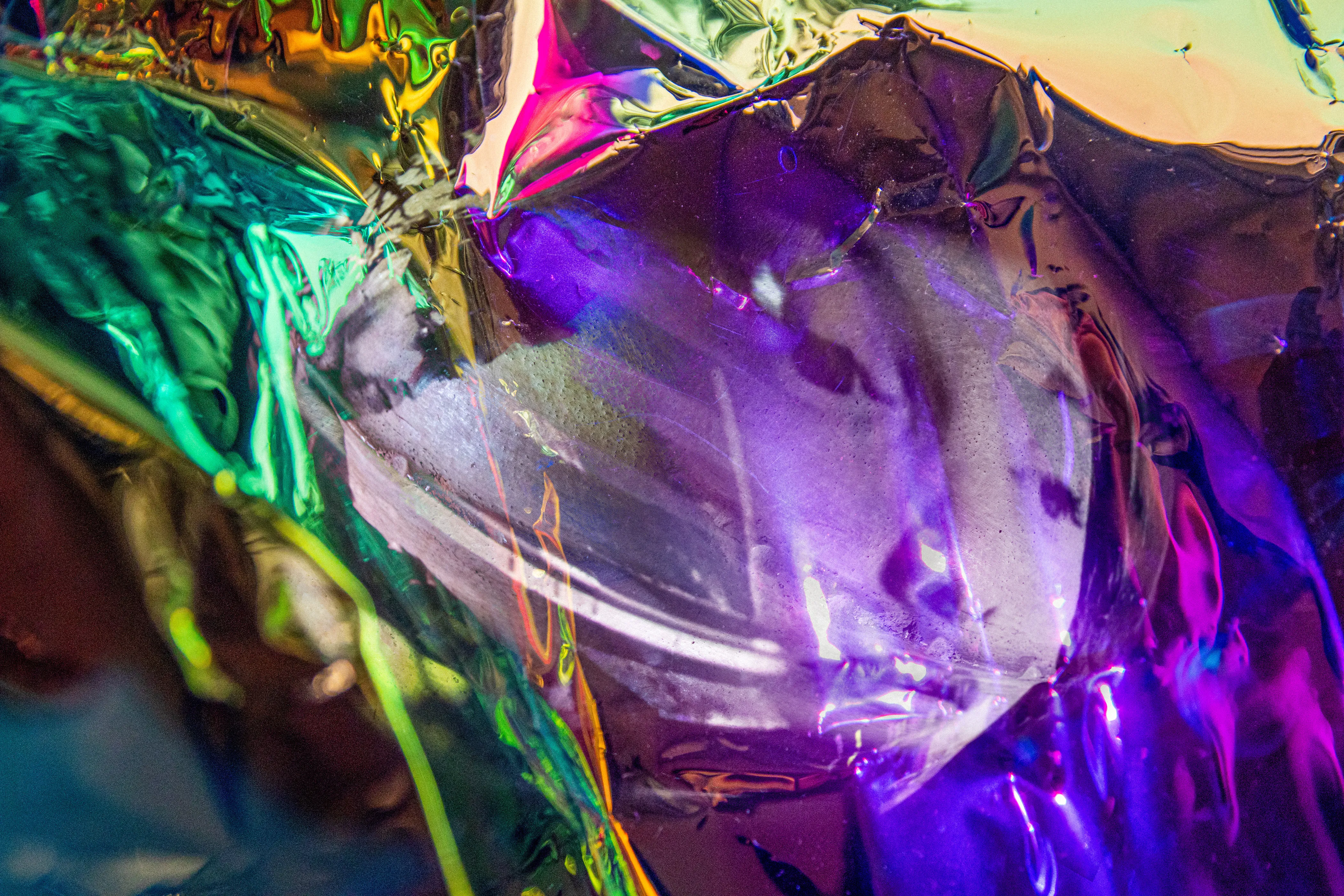 Translucent purple and green foil over a pale, mask-like face.