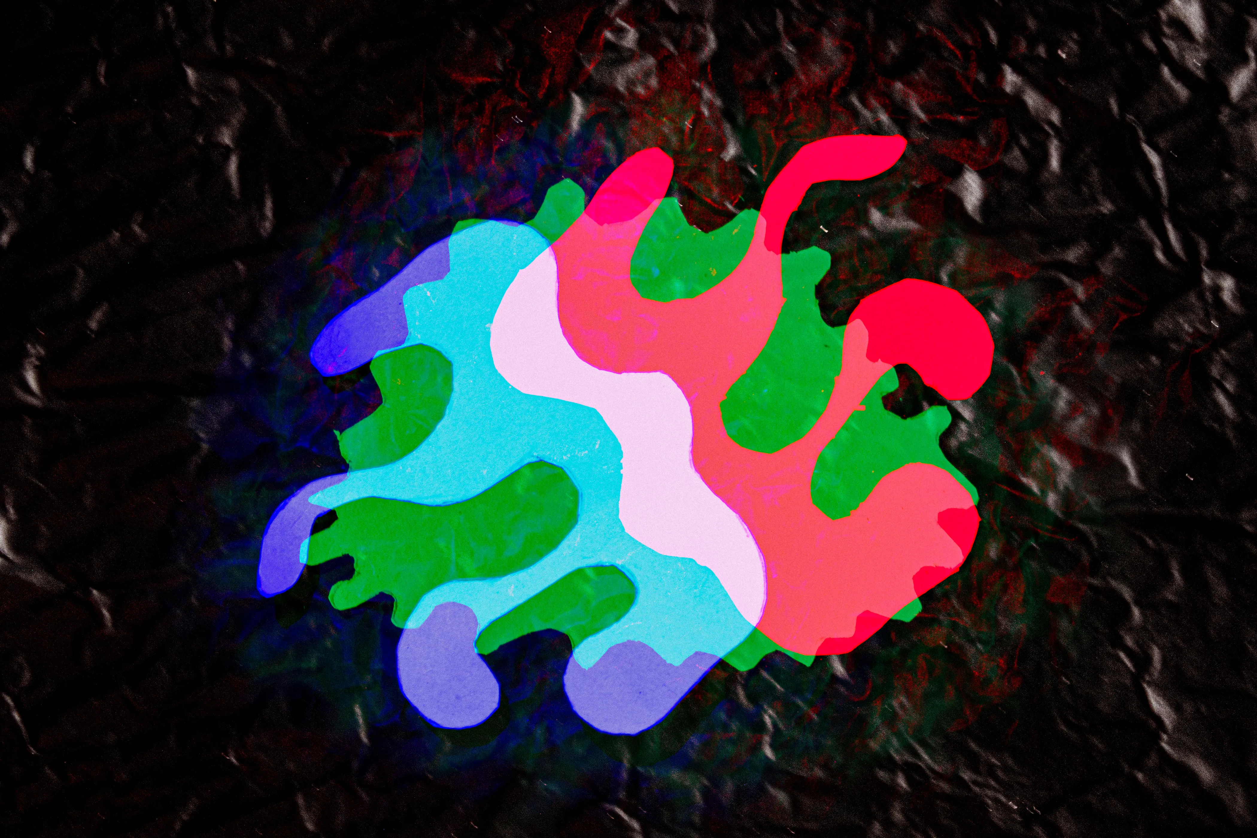 A rounded cluster of interlocking blobs in turquoise, green, pink and red, on a dark ground.