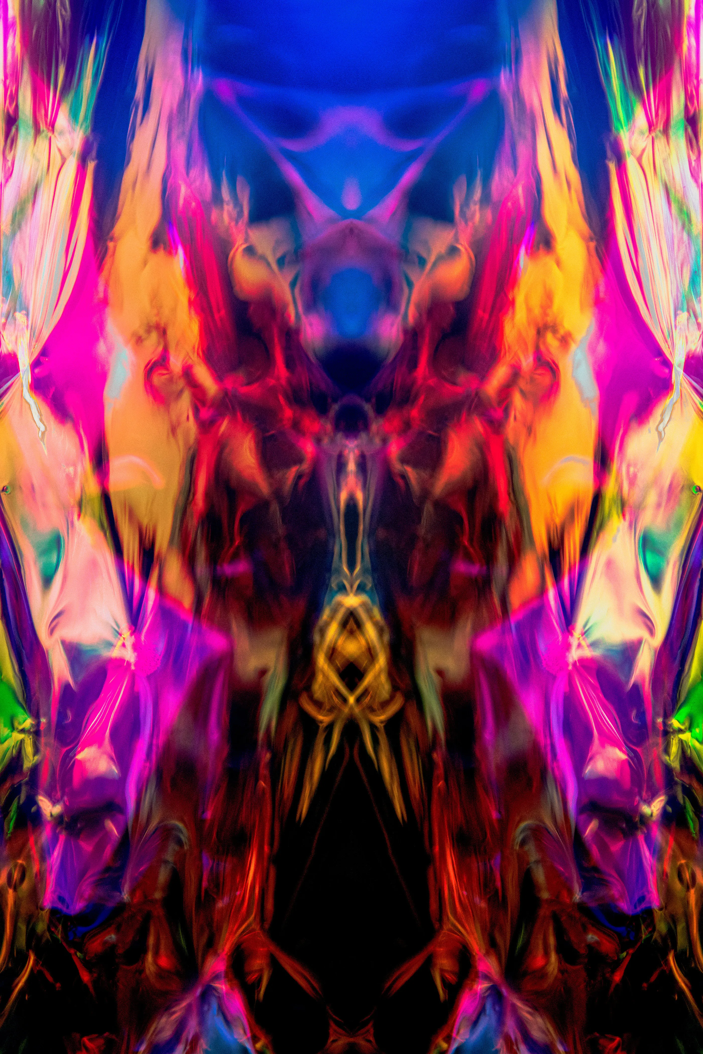 A tall mirrored composition in magenta, orange and red with dark vertical forms and a blue top.