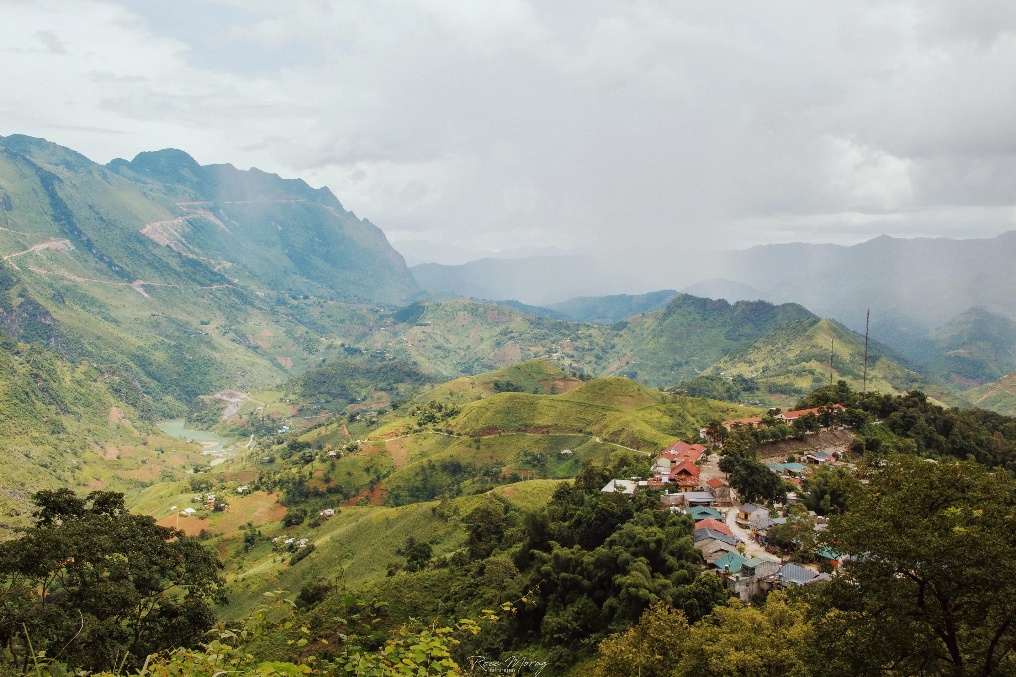 A mountain valley under a cloudy sky, with a small village among green hills.